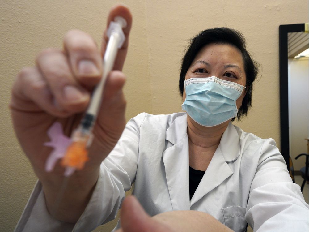 pharmacist joanna wong administers a covid-19 vaccine to a patient at market drugs medical pharmacy in edmonton on tuesday, april 13, 2021.