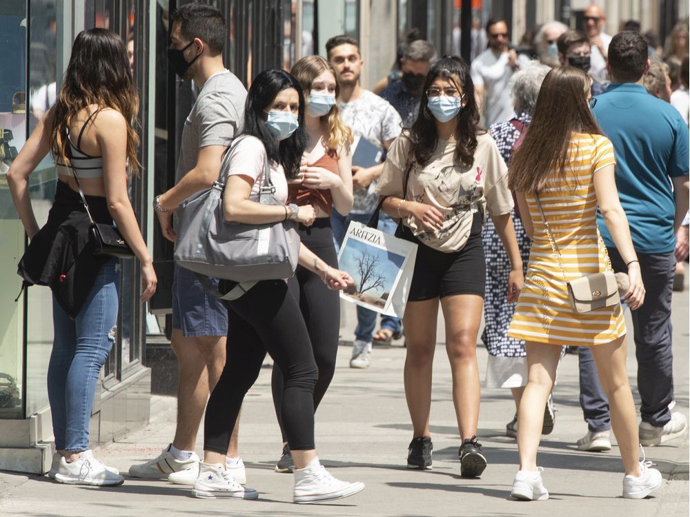 people enjoy the warm weather as they walk along ste-catherine st. wednesday, may 19, 2021 in montreal.