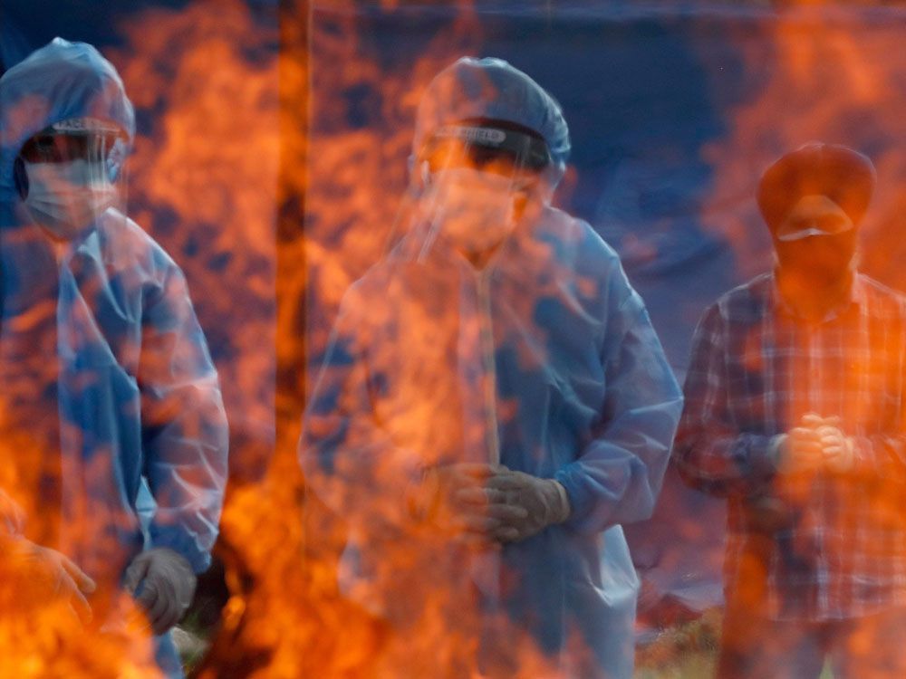 relatives stand next to the burning pyre of a man who died from the coronavirus disease during his cremation at a crematorium ground in srinagar may 25, 2021.