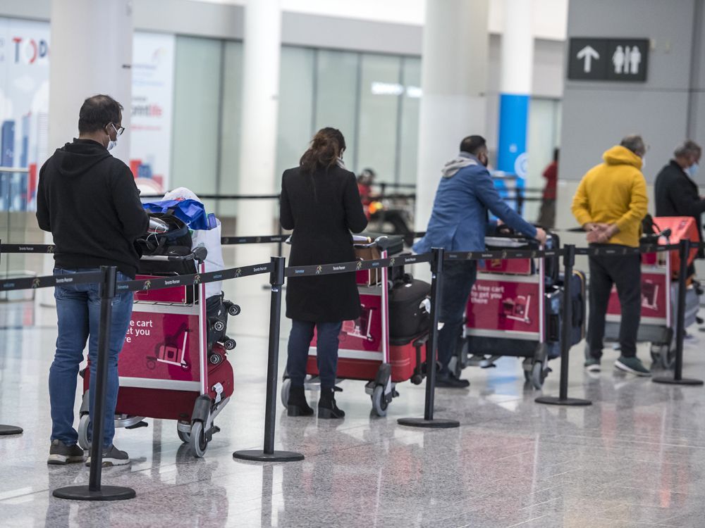 Travellers await transportation to a quarantine hotel after arriving at Pearson International Airport on Feb. 24, 2021.