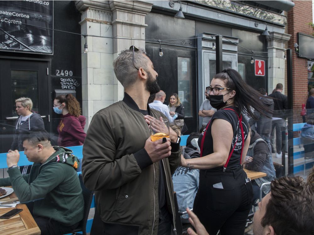 burgundy lion waitress katrina maglieri and client zafir parmar have a friendly exchange in montreal friday, may 28, 2021.