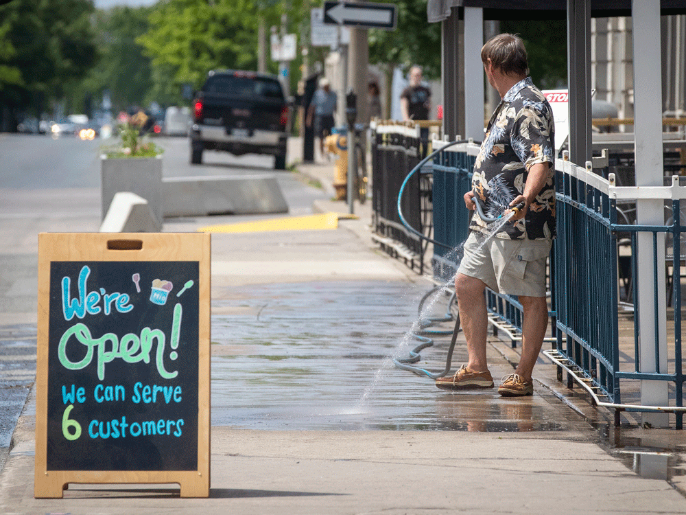 A man washes the sidewalk ahead of the opening of restaurant patios in Kingston this week as Ontario begins easing up on COVID-19 pandemic restrictions. People are likely to react to reopenings in different ways with some jumping in with both feet while others feel anxious.