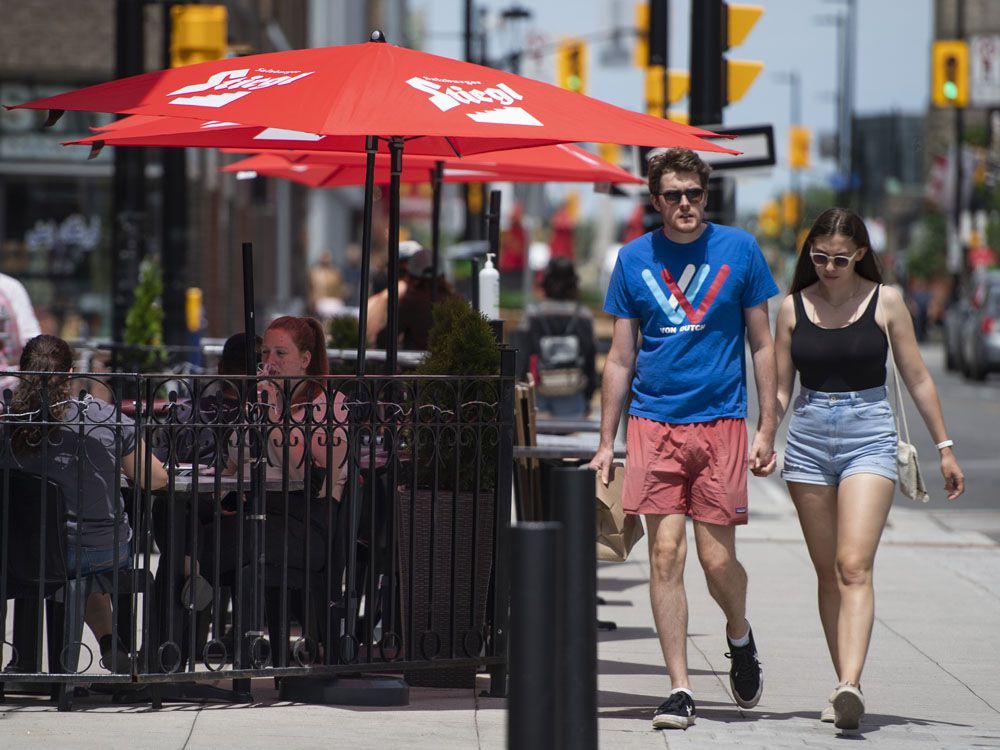 people walk past a patio open for business in ottawa on the first day of ontario's first phase of re-opening amidst the third wave of the covid-19 pandemic, on friday, june 11, 2021.