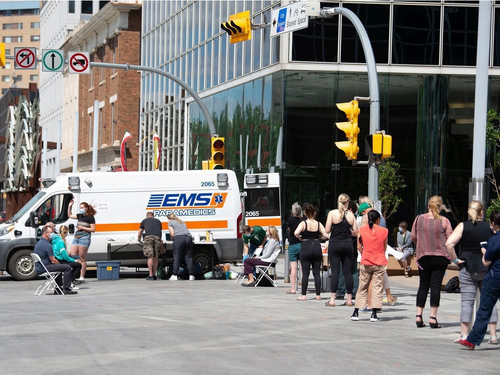 people stand in line for vaccinations at a pop-up covid-19 vaccine clinic on scarth street in regina, saskatchewan on june 16, 2021.