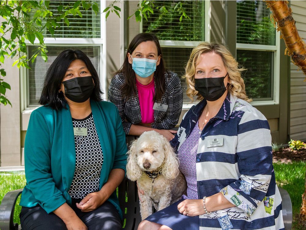 preston park retirement residence i office manager joann lee, activities director meghan arnault, and executive director jodi gronsdahl (left to right) sit with dog scrubs.