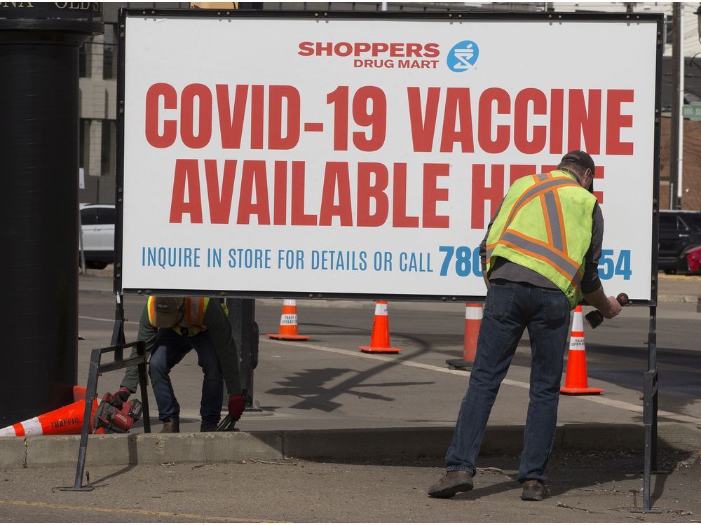 crews set up a covid-19 vaccine sign outside a shoppers drug mart, 8065 104 st., in edmonton, on may 5, 2021.