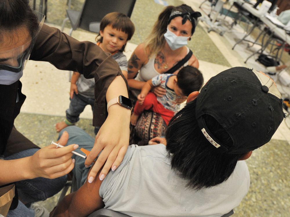 long ly, accompanied by partner kiera bonifacio and their kids vough, 3, and van, 1, gets his first covid-19 jab at the italian cultural centre in vancouver on aug. 25, 2021.