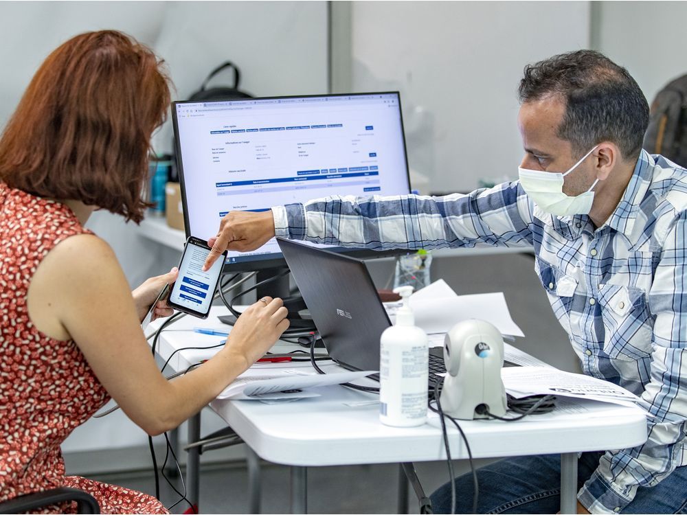 ciusss du centre-ouest employee mohamed imhidi helps valerie kuzmina create her vaccine passport at the décarie square vaccination clinic in montreal on aug. 30, 2021. kuzmina needed help getting her ontario vaccinations registered in quebec.