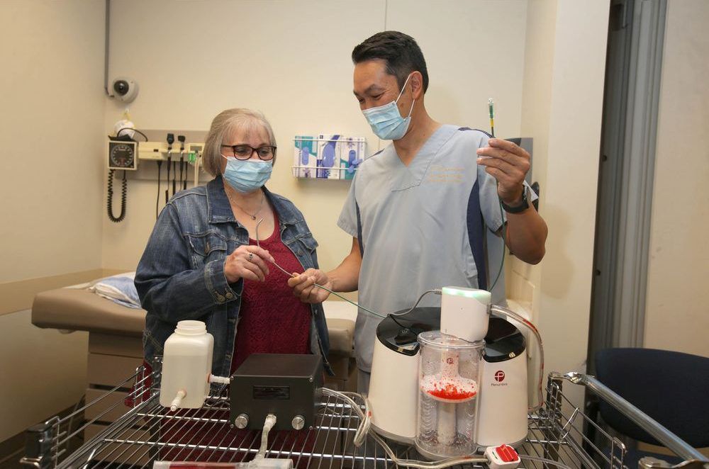 brenda crowell (l) speaks with interventional radiologist dr. jason wong at foothills hospital in calgary and is shown the indigo lightening cat12 on thursday, august 19, 2021. the new device was used on crowell to quickly extract blood clots from her lungs in may. the device used for the first time in canada saved crowell's life after she developed a blood clot caused by covid-19. jim wells/postmedia