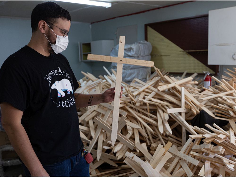 jason mercredi holds one of 1,600 crosses made to commemorate saskatchewan people who died of overdose.