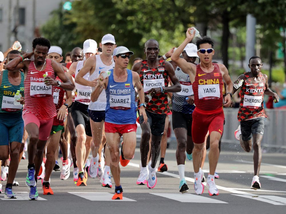 Runners sprinkle water at the refreshment point while competing in the men's marathon final during the Tokyo 2020 Olympic Games in Sapporo on August 8, 2021. Researchers' observation that competitive running is an injury risk could be related to a number of factors, including high volume training and failure to let the body fully recover between hard training runs, Jill Barker writes.