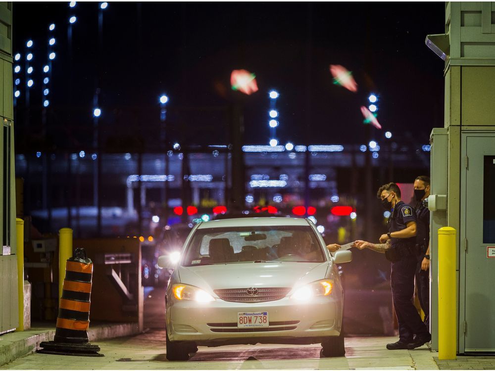 a canada border services agency officer hands a traveller their documentation back as other travellers line up behind them to enter canada after border restrictions were loosened to allow fully vaccinated u.s. residents, after the coronavirus disease (covid-19) pandemic forced an unprecedented 16-month ban, at the thousand islands bridge crossing in lansdowne, ontario, canada, august 9, 2021.