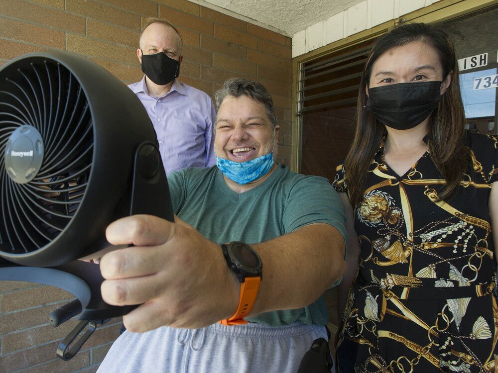 new westminster-burnaby mp peter julian (left) and burnaby-deer lake mla anne kang give a fan to andy majta in burnaby as part of the caring project.