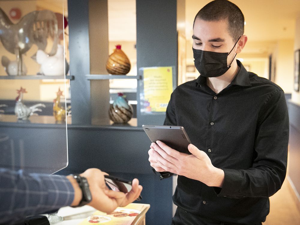 a worker scans a qr code from client at cora restaurant in downtown montreal.