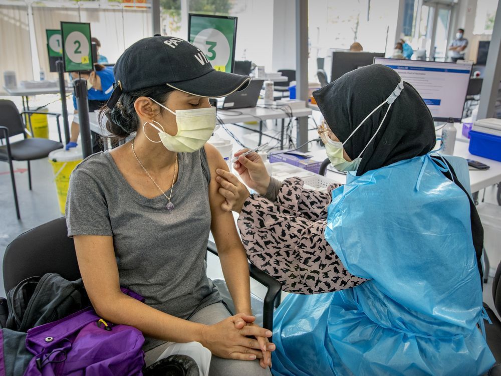 "the world is edging toward 5 million deaths from covid-19," lise ravary writes. "when are we all going to get the message?" above: nurul akidah lukman administers a dose to daisy salgado at a covid-19 vaccination site on park ave.