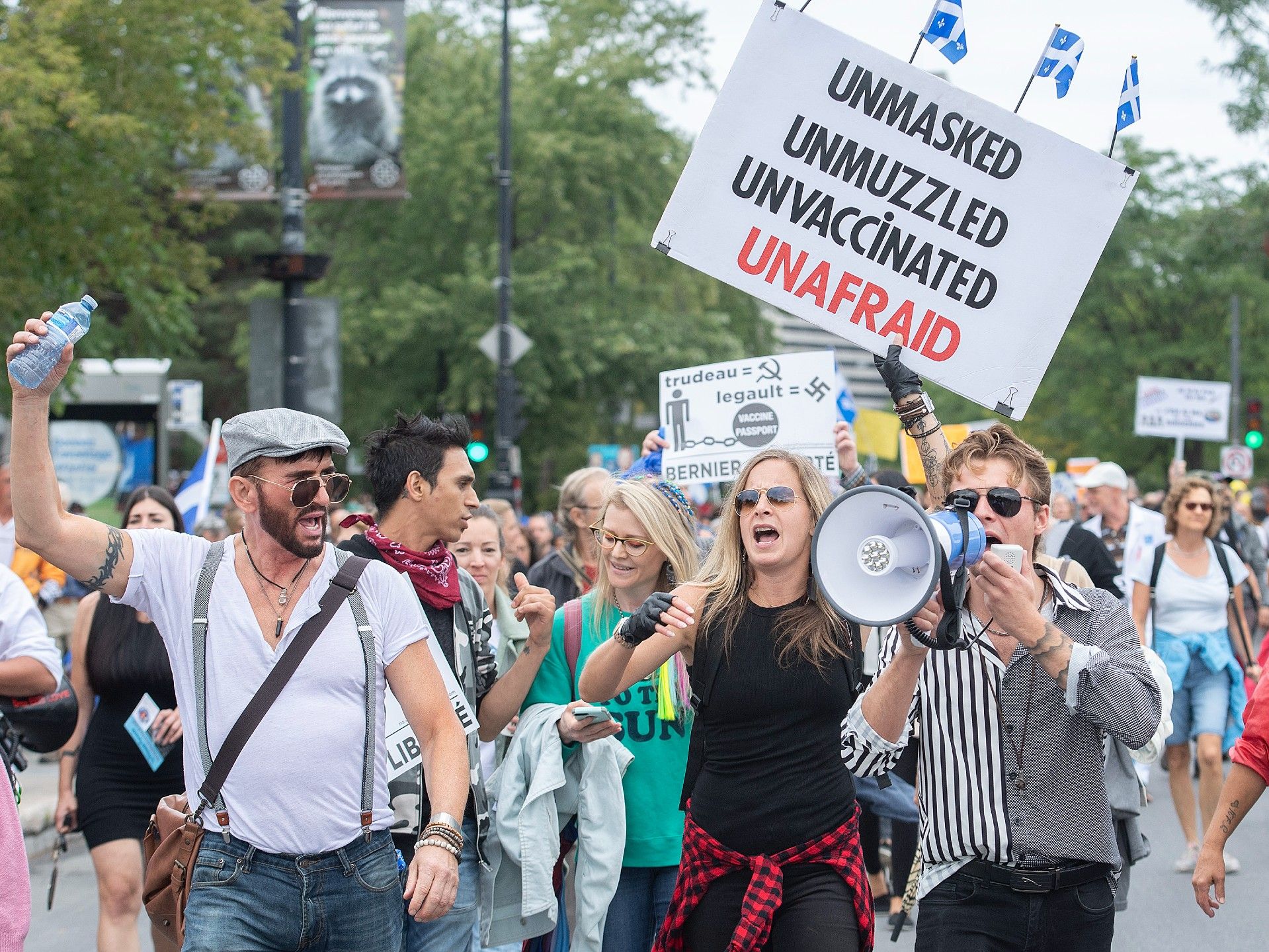 People hold up signs at a demonstration opposing the Quebec government’s measures to help stop the spread of COVID-19 in Montreal on Aug. 28. (Graham Hughes / The Canadian Press)