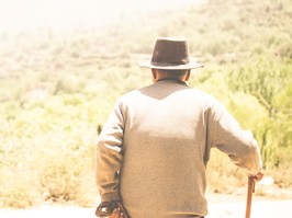 Old man with cane looking at field