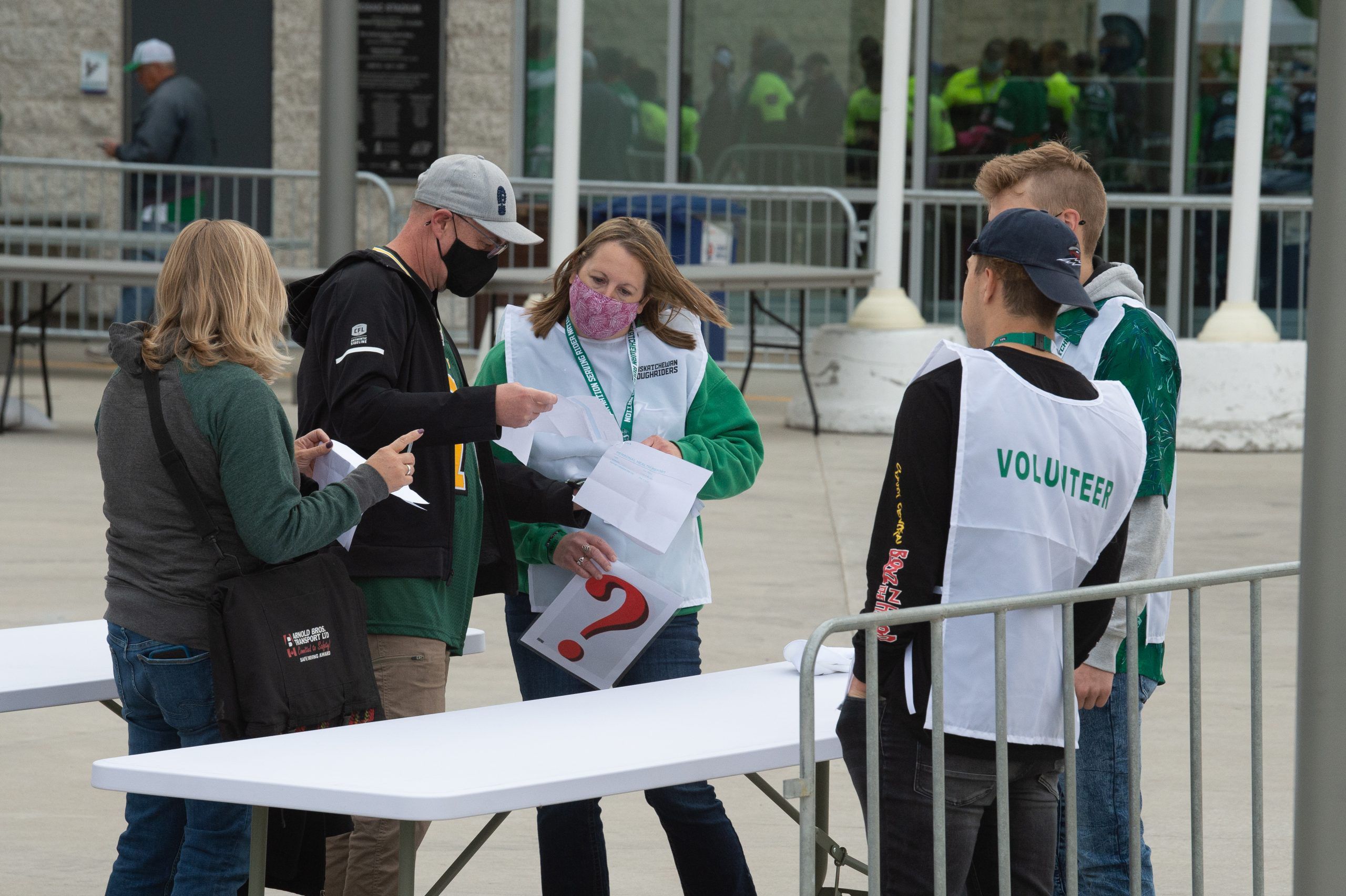 attendants check covid-19 vaccination status of ticketholders prior to a cfl football game between the saskatchewan rougriders and the toronto argonauts at the entrance to mosaic stadium in regina, saskatchewan on sept. 17, 2021.