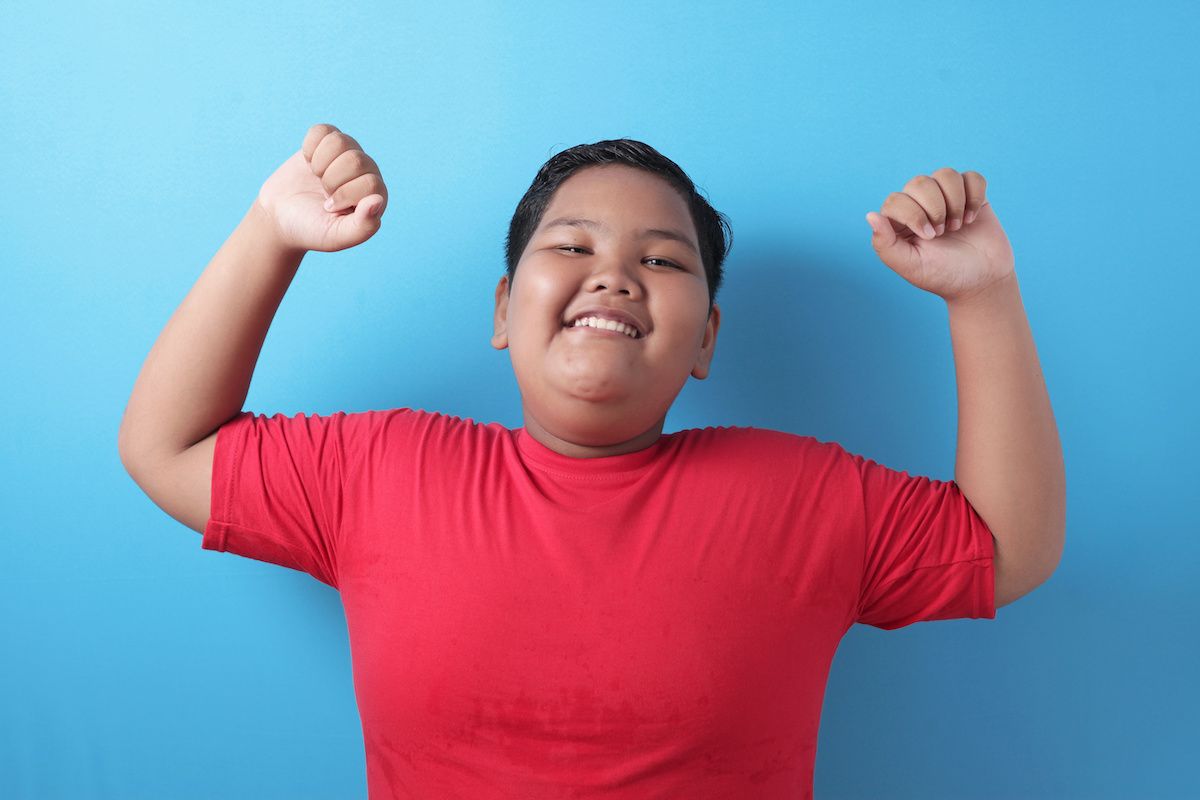 Confident kid shows his biceps arm muscle