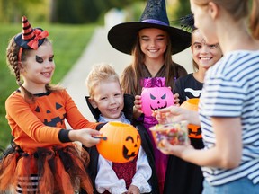 Woman giving treats to children in Halloween costumes