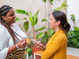 Brazilian business woman talking causally with co-workers.outside in the garden. Candid, connection, break, relaxation, chatting concept.