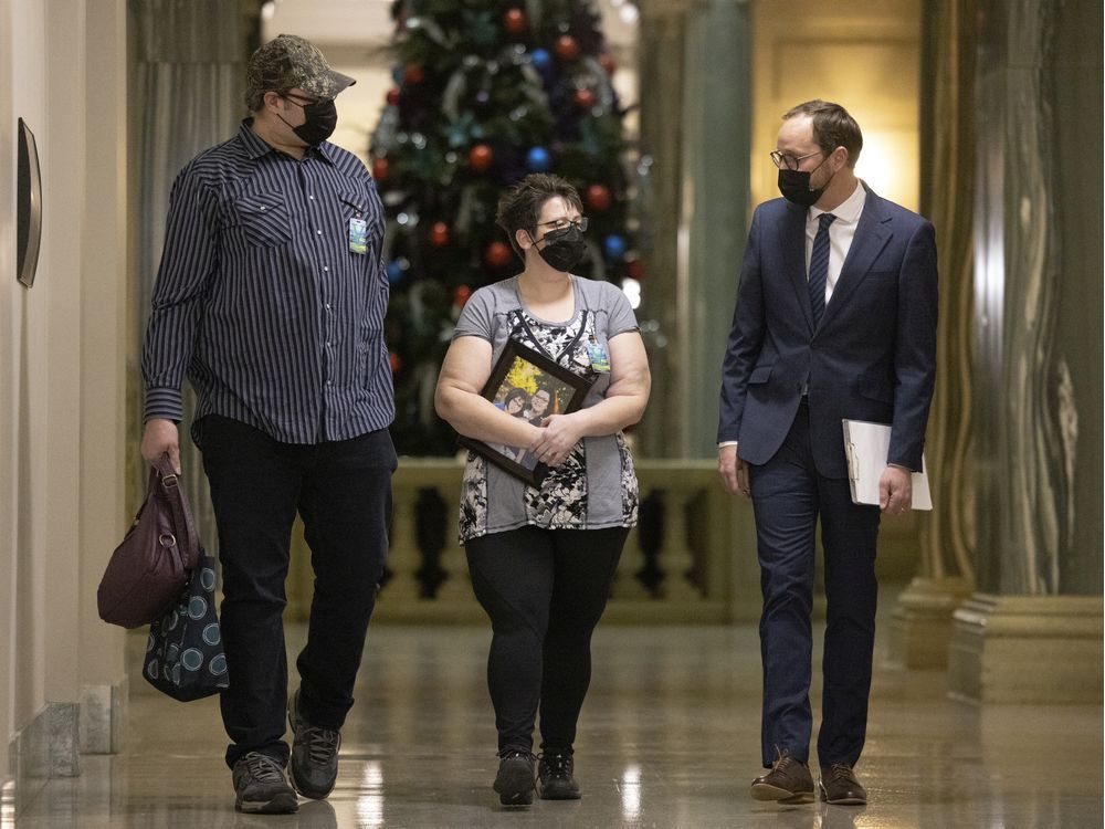 stephanie brad and her husband mike speak with ndp leader ryan meili at the legislative building after speaking with reporters about her cancelled surgeries. brad held a photo of her four daughters while speaking at the legislative building.