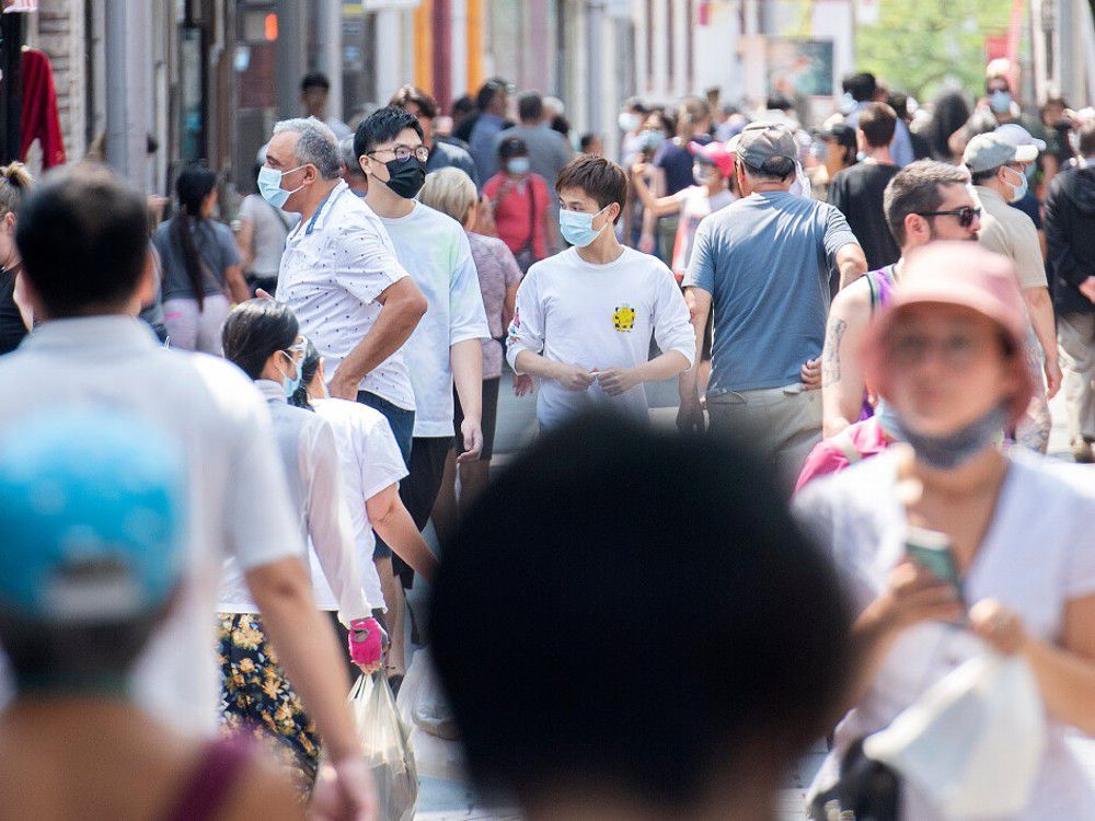 people wear face masks as they walk along a street in montreal, sunday, august 8, 2021, as the covid-19 pandemic continues in canada and around the world.