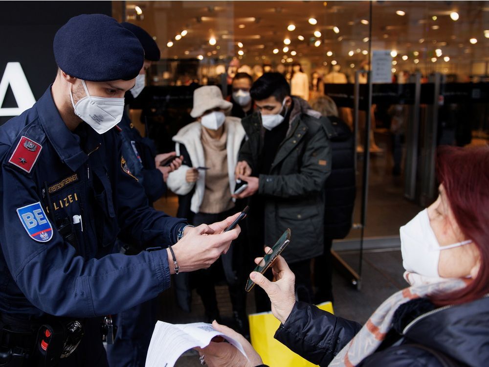 police officers check the vaccination status of shoppers at the entrance of a store in vienna on tuesday, november 16, 2021 after the austrian government imposed a lockdown on roughly two million people who are not fully vaccinated against covid-19.