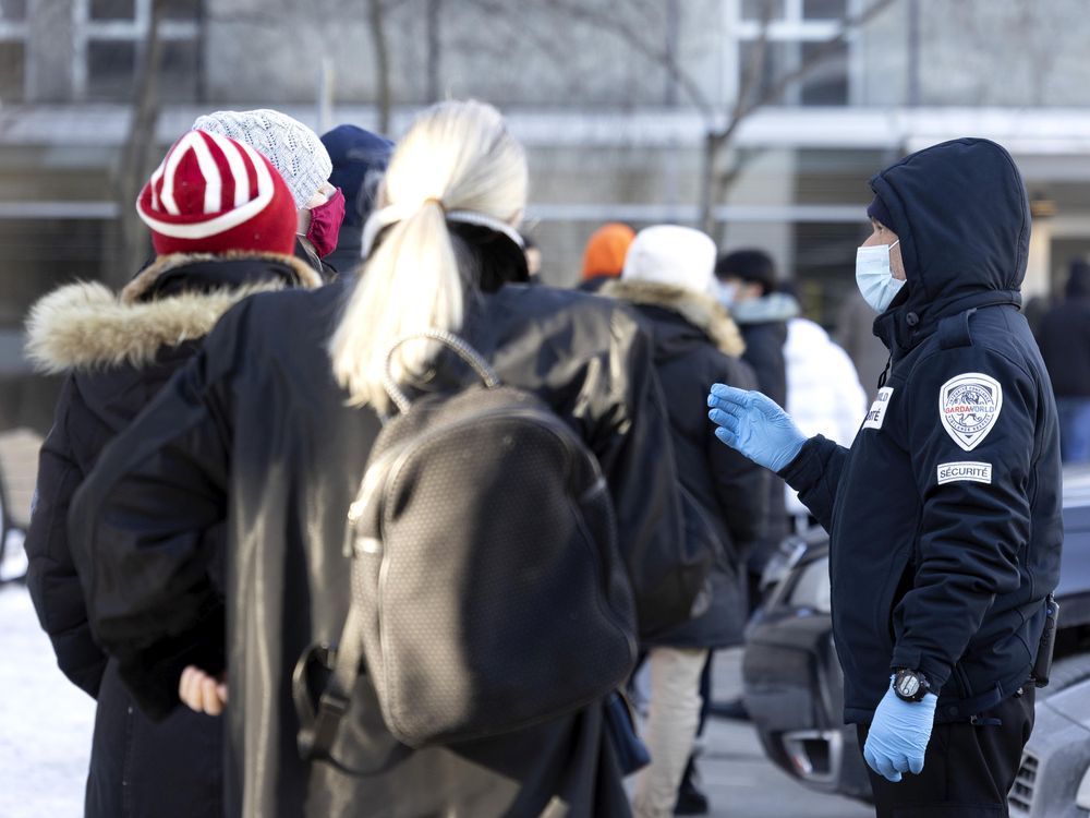 a security guard helps manage the line for covid-19 tests at the hôtel dieu testing site in montreal on friday, dec. 24, 2021.