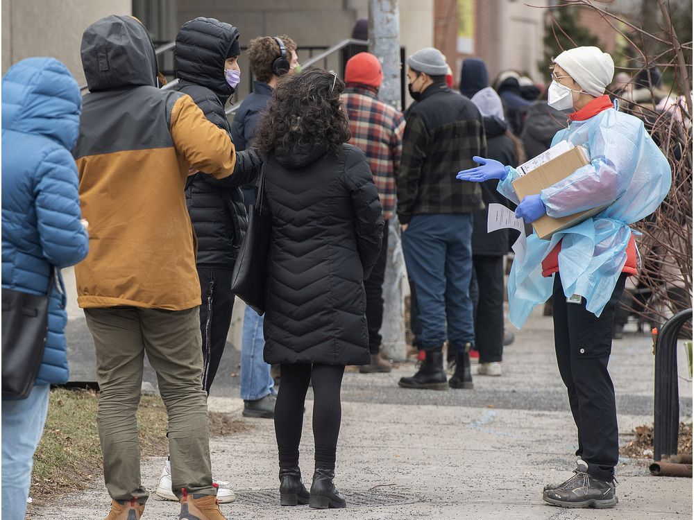 a health-care worker talks to people as they wait to receive a covid-19 test in montreal on friday, dec. 17, 2021.