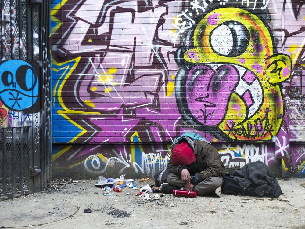 a man sits slumped over, surrounded by drug paraphernalia, in an alley behind the 100-block east hastings street in vancouver on thursday, february 11, 2021.