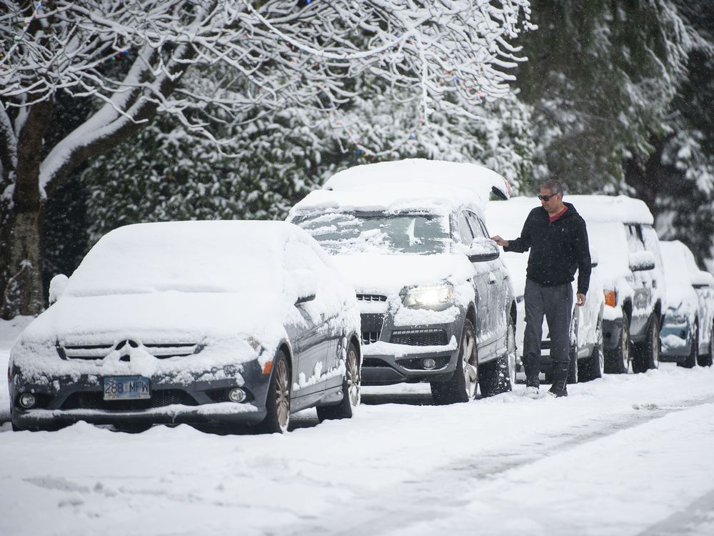 a man clears snow from his car in north vancouver on dec. 25, 2021.