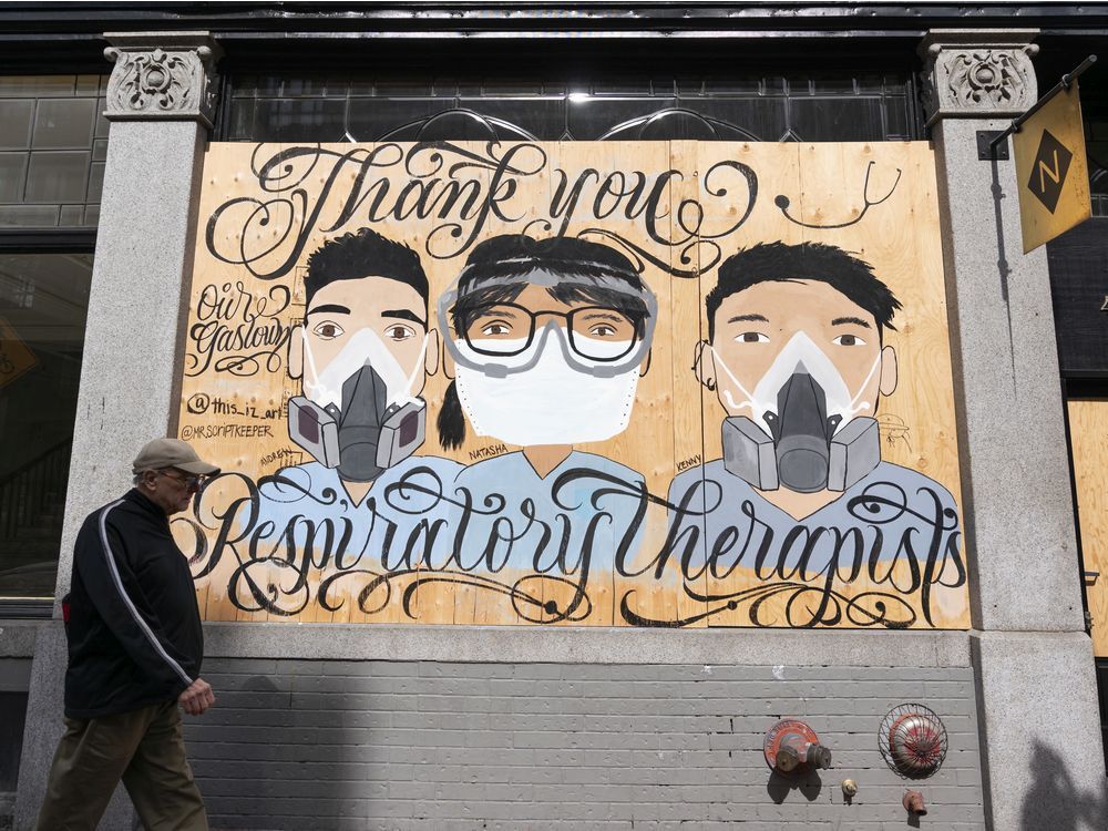 a man walks past a murals painted on the side of a building in gastown that honours respiratory therapists during the battle against the spread of the covid-19 virus.