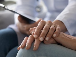 Young woman doctor holding hand of senior grandmother patient, closeup