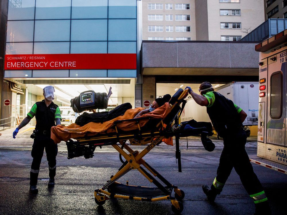 ambulance crew members deliver a patient at mount sinai hospital in toronto as officials warned of a "tsunami" of new coronavirus disease (covid-19) cases in the days and weeks ahead due to the omicron variant.