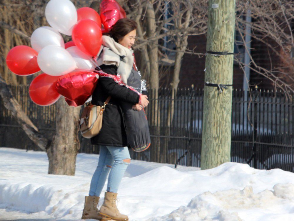 A young woman walks on Bagot Street in Kingston, Ont. on Wednesday January 31, 2018 with numerous Valentine's Day balloons in tow.
