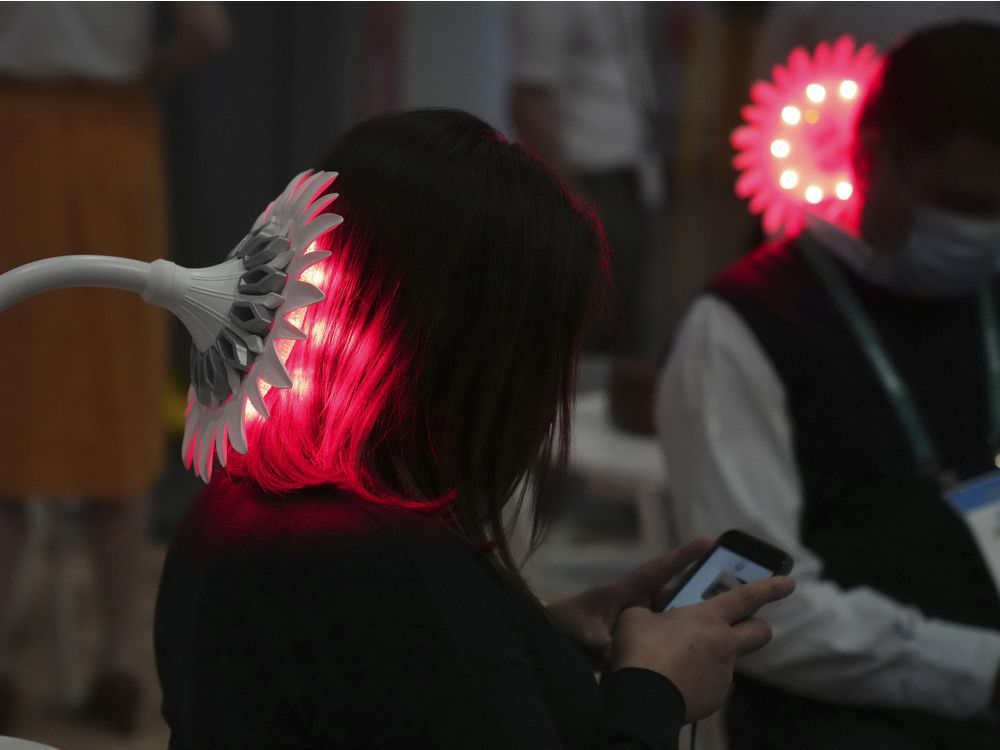 Attendees try out light therapy during the CES tech show Thursday, Jan. 6, 2022, in Las Vegas.