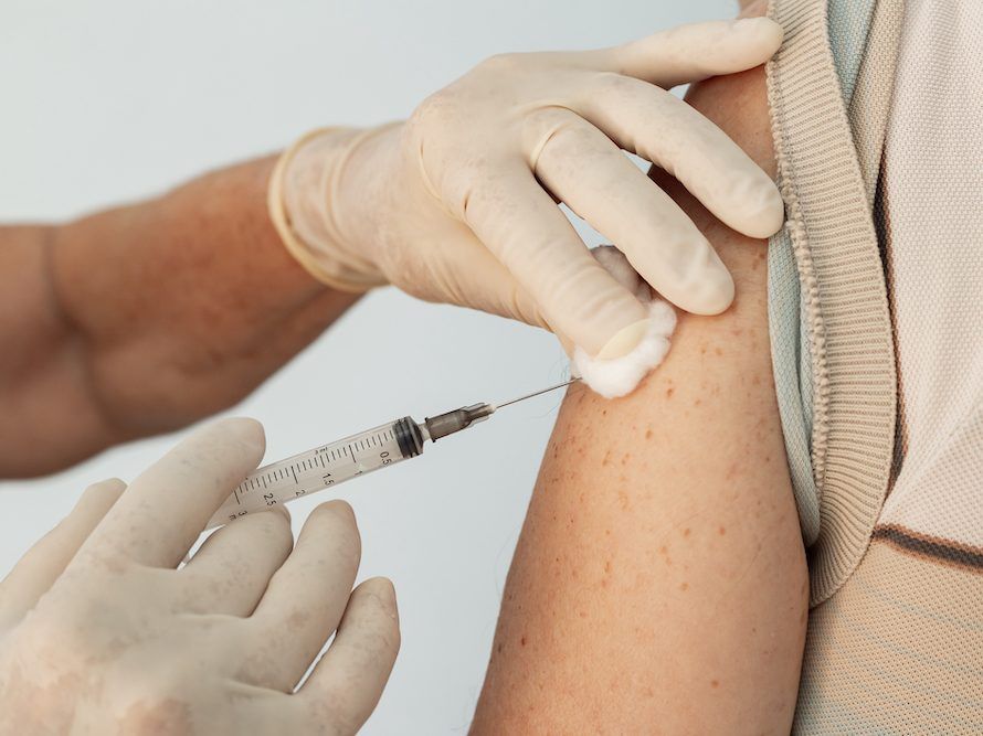 Closeup on nurse hands applying vaccine to elderly patient.