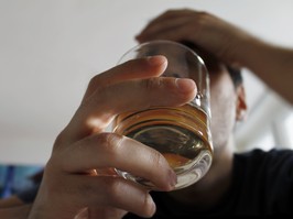 man holding glass of liquor, long angle