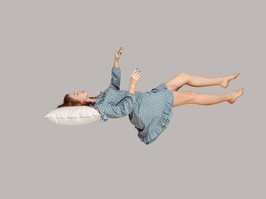 Sleeping beauty floating in air. Relaxed girl in vintage ruffle dress keeping eye closed, lying on pillow levitating