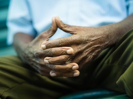 closeup of hands of elderly african american man sitting on bench