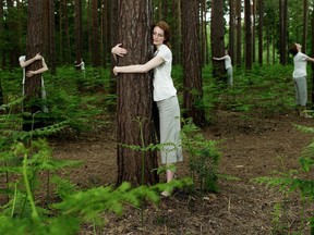 Identical women hugging trees in forest (digital composite)