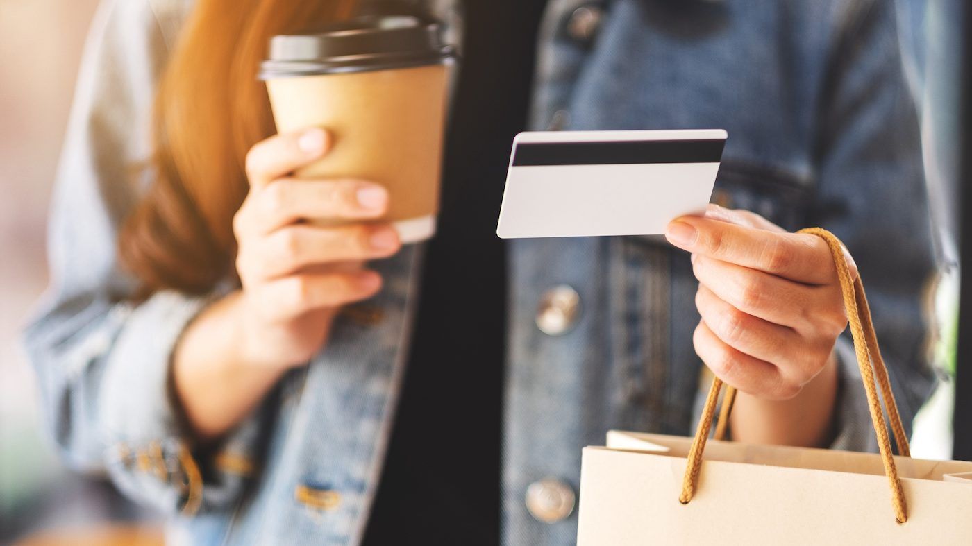 Person holding credit card and coffee