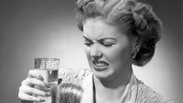woman looking at glass of water in disgu