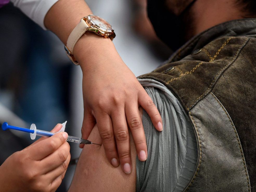 A nurse inoculates a man with a booster dose of vaccine against COVID-19 on Feb. 15, 2022.