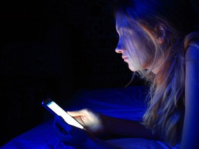 young woman using the smart phone on bed before sleep