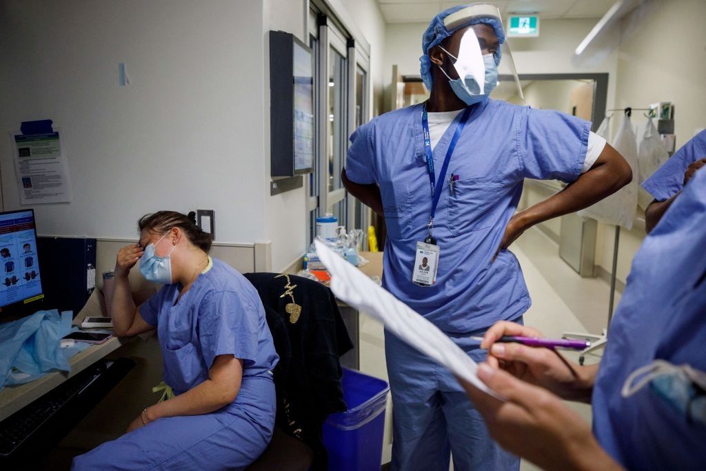 A nurse holds her head as nurses care for patients suffering from coronavirus disease (COVID-19) at Humber River Hospital's Intensive Care Unit, in Toronto, Ontario, Canada, on April 28, 2021. (Photo by COLE BURSTON/AFP via Getty Images)