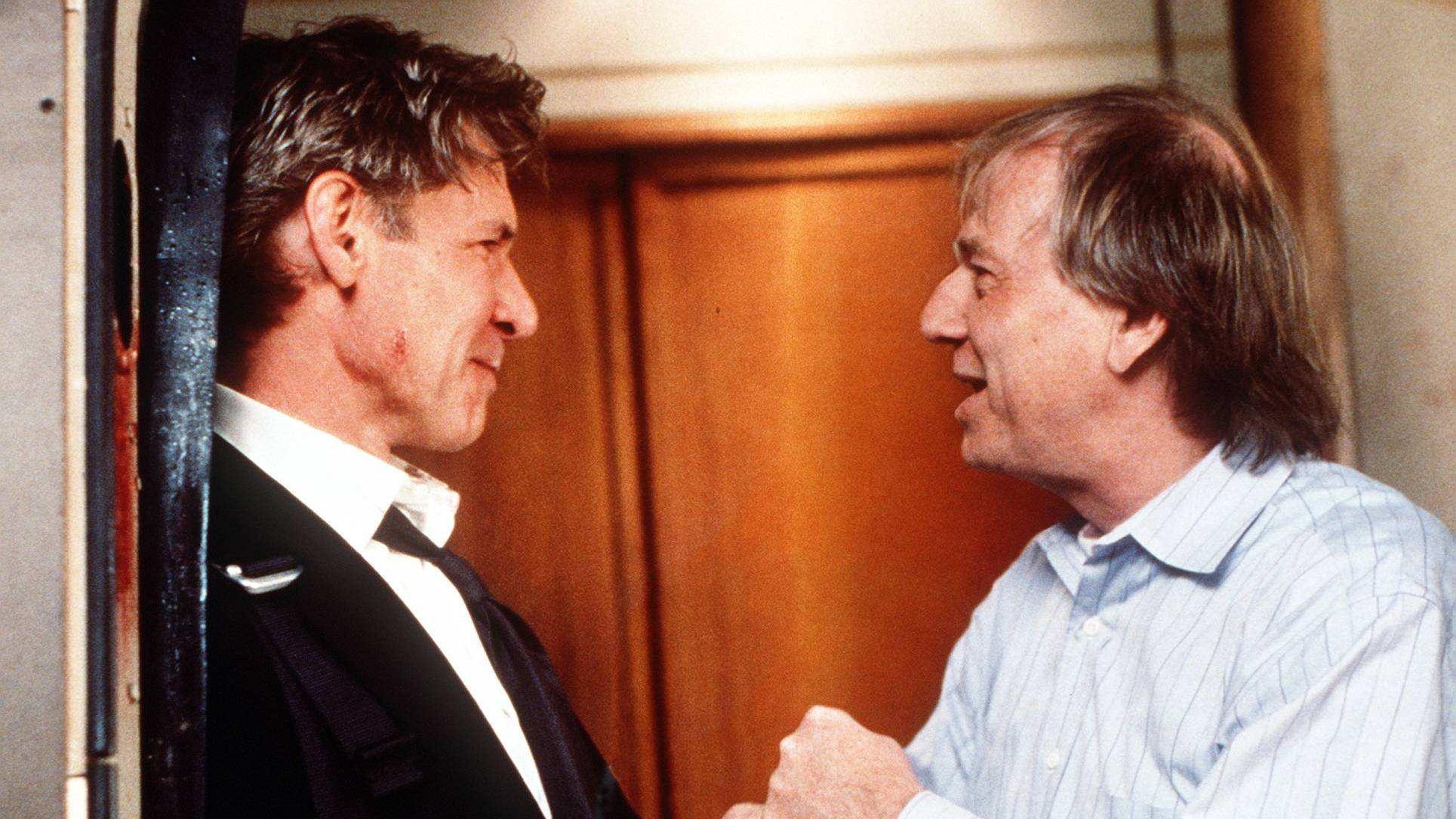 Director Wolfgang Peterson (right) discusses a scene with Harrison Ford on the movie set of "Air Force One." 