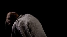 Hunchback beggar on black background, spinal diseases in old age, kyphosis