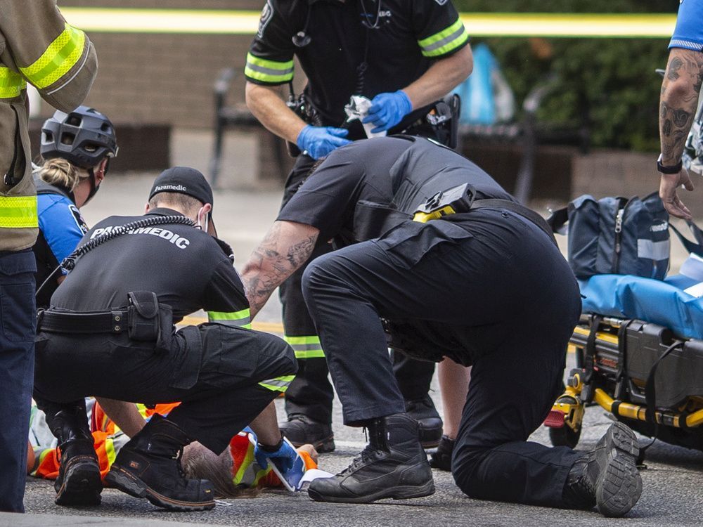 windsor police and ems paramedics treat a man suffering from a gun shot wound after he was shot by police while threatening people with a machete on wyandotte street west at ouellette avenue, on monday, august 15, 2022.